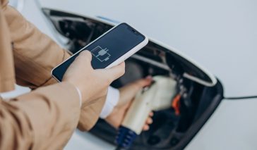 Woman holding charger and charging electric car close up