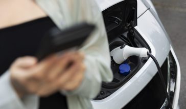 woman-using-her-smartphone-while-electric-car-is-charging